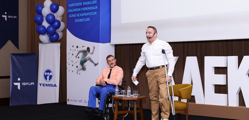 Resim: Sahnede, tekerlekli sandalyede oturan Prof. Dr. Ozan Bahar ve yanında ayakta, koltuk değneği kullanan sosyolog Mehmet Kızıltaş yer alıyor. Kızıltaş konuşma yaparken, Bahar dikkatle onu dinliyor. Arka planda TEMSA ve İŞKUR logoları ile etkinlik afişi görülüyor.